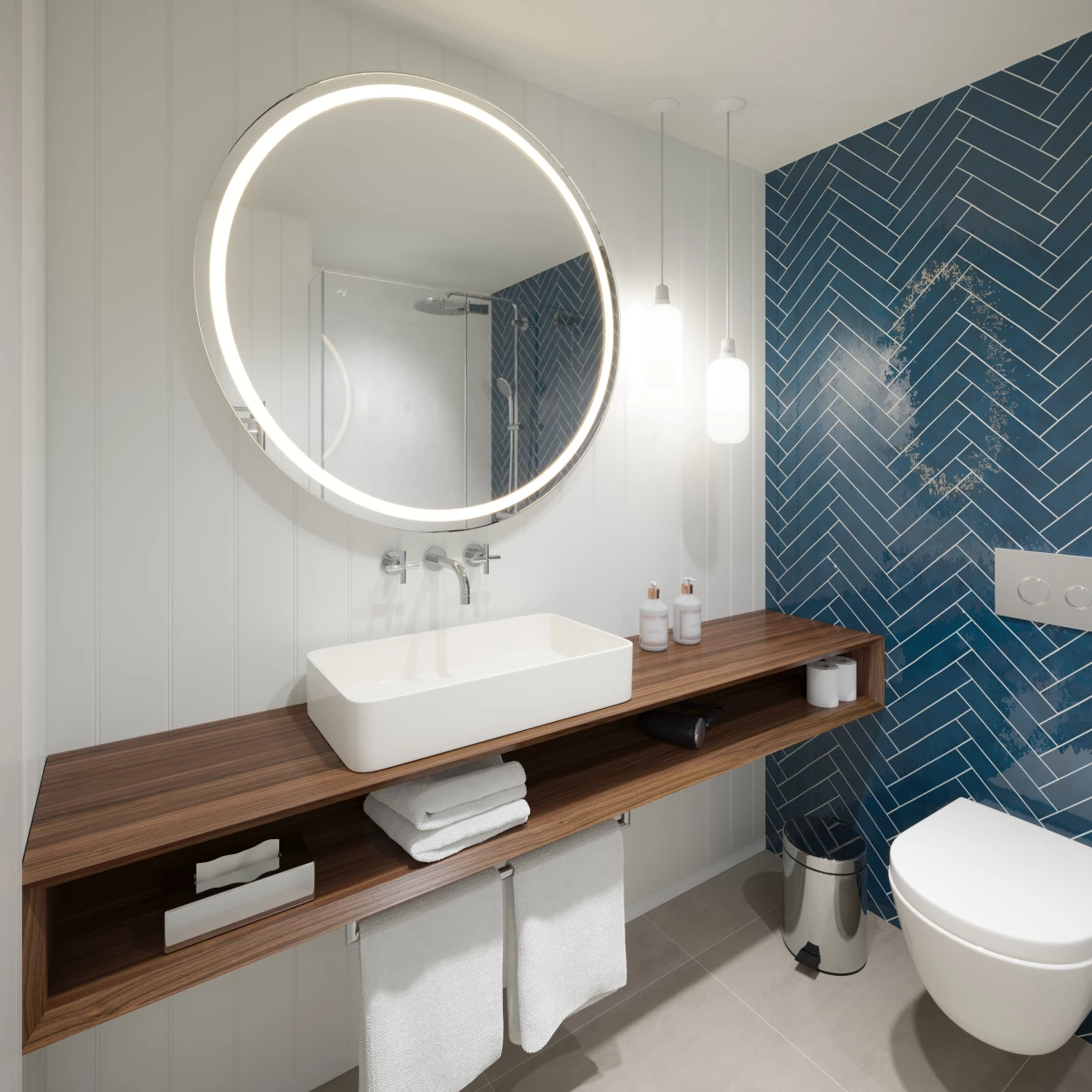Badezimmer mit rundem Spiegel und blauer Kachelwand