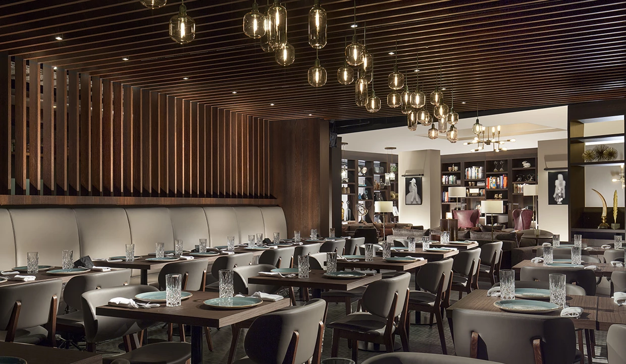 Elegante Restaurantbestuhlung mit Pendelleuchten und Holzverkleidung