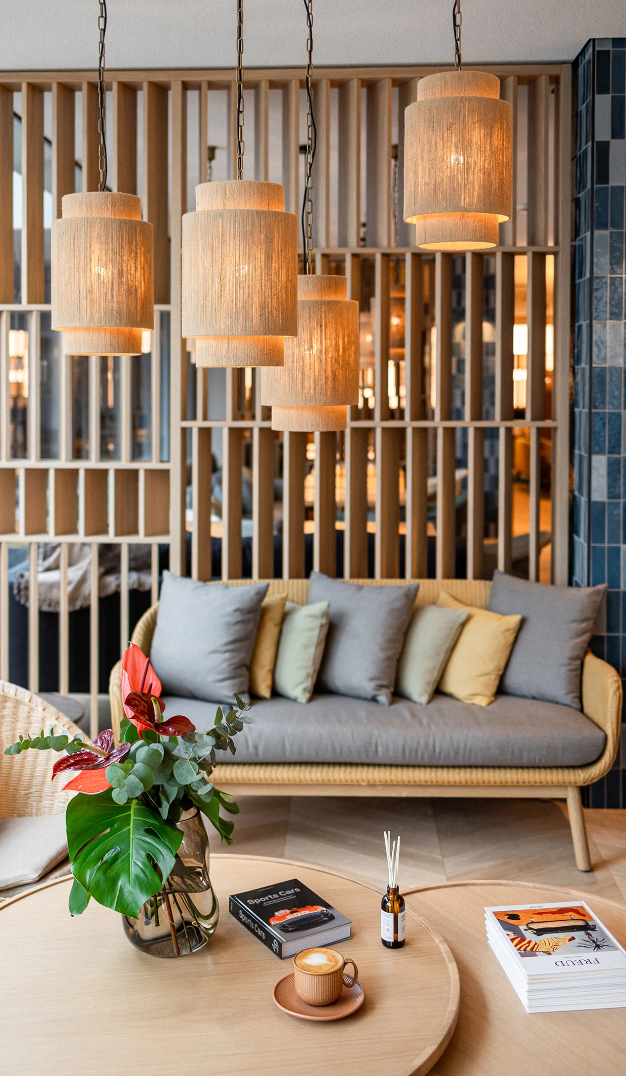 Gemütlicher Sitzbereich mit Sofa, Kissen, Hängelampen und Tisch mit Blumen