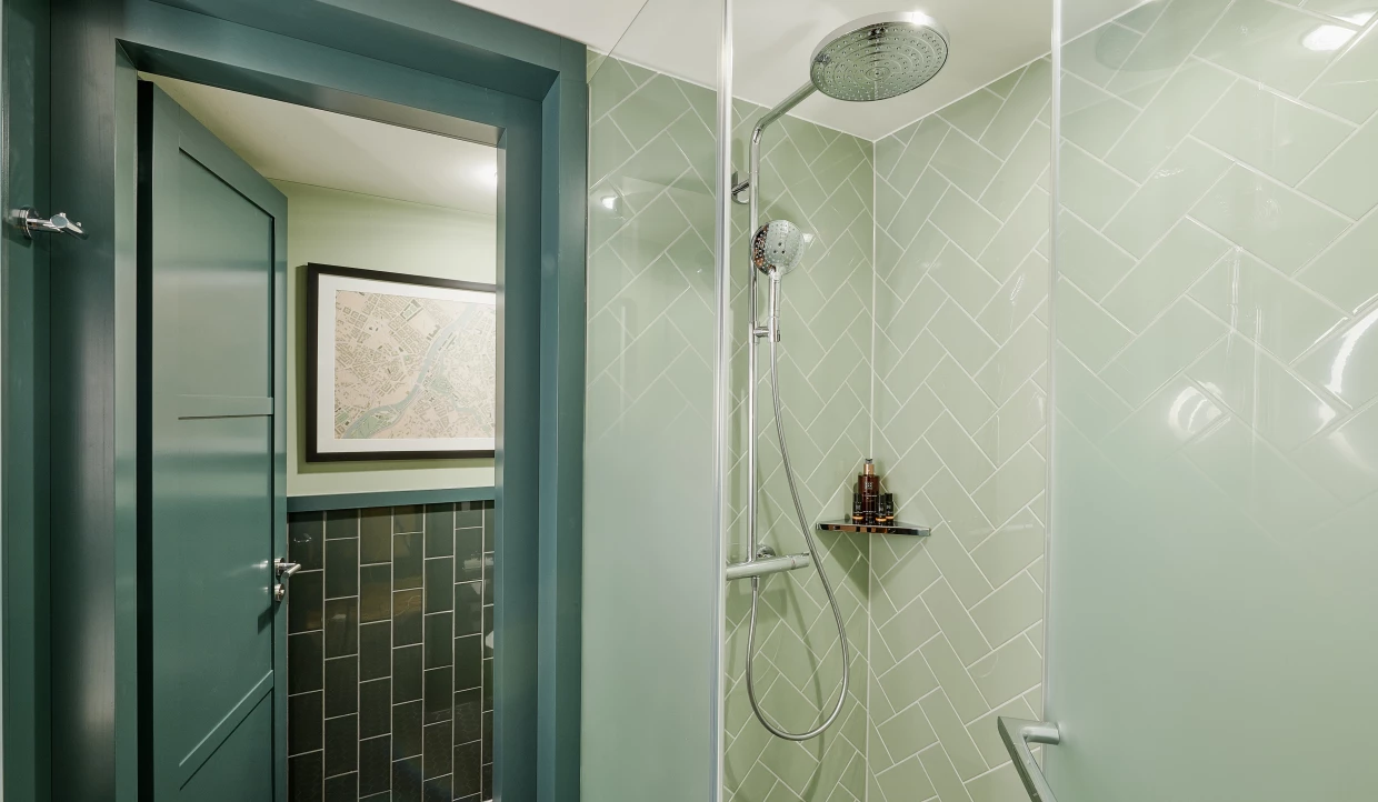Hotel-Badezimmer in verschiedenen Grüntönen mit Regendusche und historischem Stadtplan als Wandbild