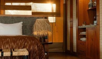 Holzlampe und Nachttisch neben einem Bett im Zelt