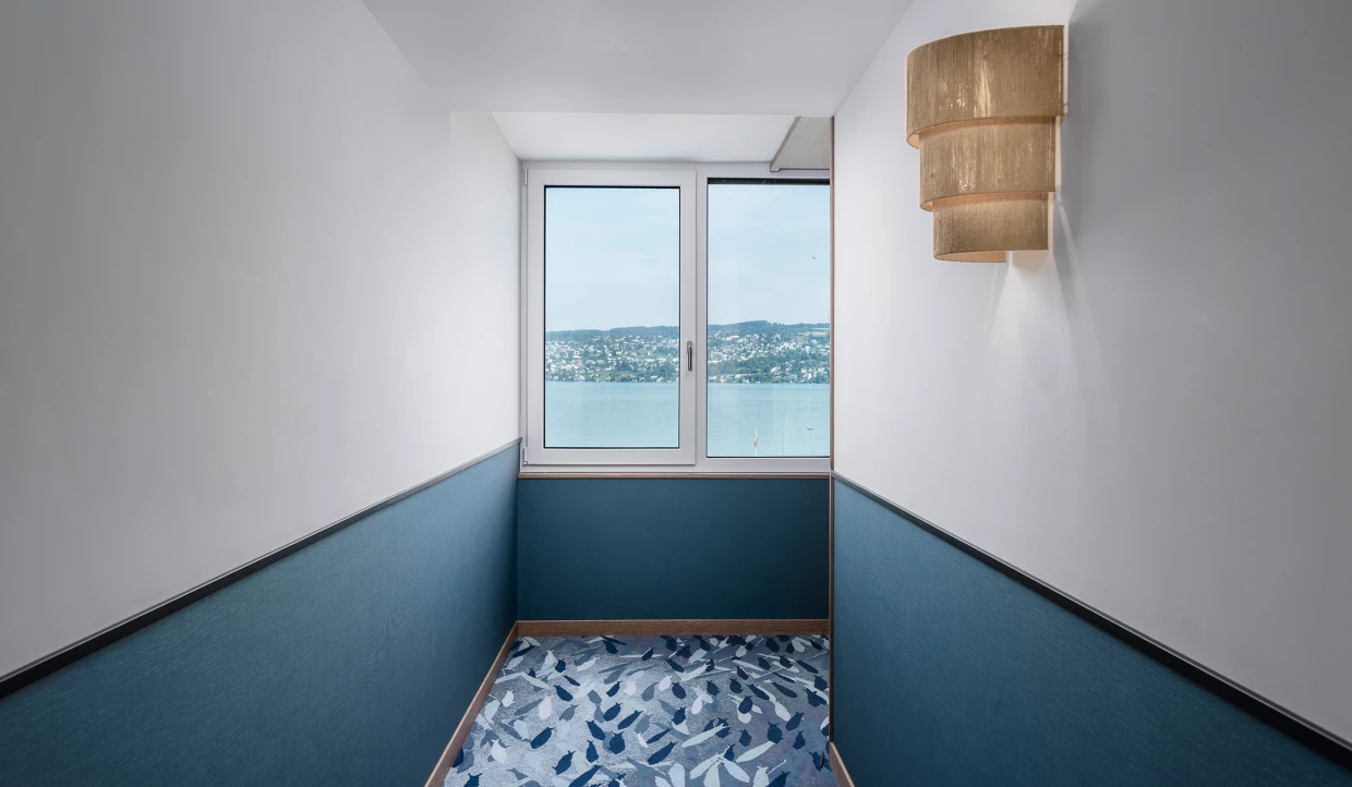 Hotelflur mit Fensterblick auf See und dekorativem Teppich