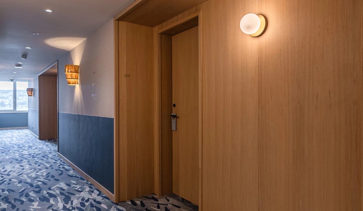 Hotelflur mit Holztüren, Teppichboden und Wandlampen
