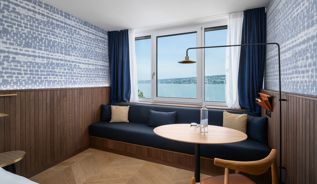 Hotelzimmer mit Fensterblick auf See, Sofa und Tisch