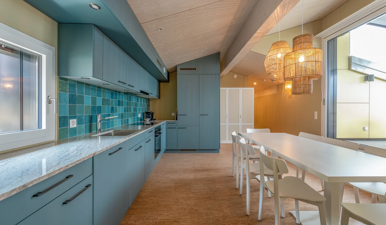 Moderne Küche mit langen blauen Schränken und Esstisch