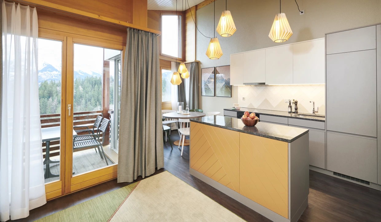 Modern kitchen with island, pendant lights, and dining area near balcony door