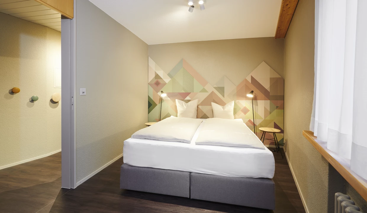 Modernes Schlafzimmer mit Doppelbett und geometrischer Wandgestaltung
