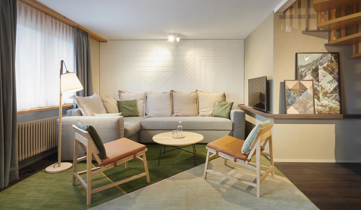 Modernes Wohnzimmer mit grauem Sofa, runden Tisch und zwei Holzstühlen