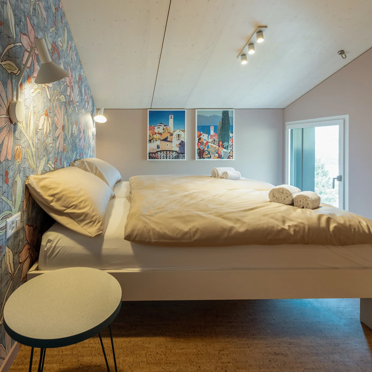 Schlafzimmer mit Blumenwand, Doppelbett und gerollten Handtüchern