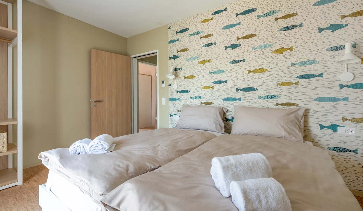 Schlafzimmer mit Fischmuster-Tapete und zwei grauen Kissen