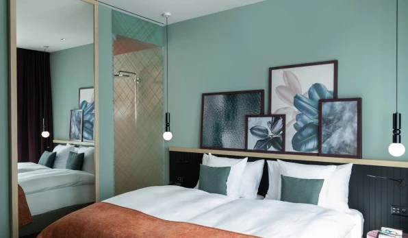 Stylish hotel room with double bed and botanical motifs on the wall.