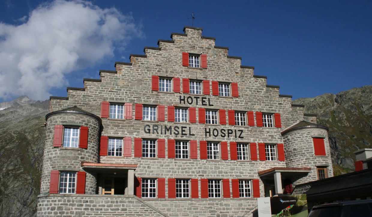 Steingebäude mit roten Fensterläden unter blauem Himmel.