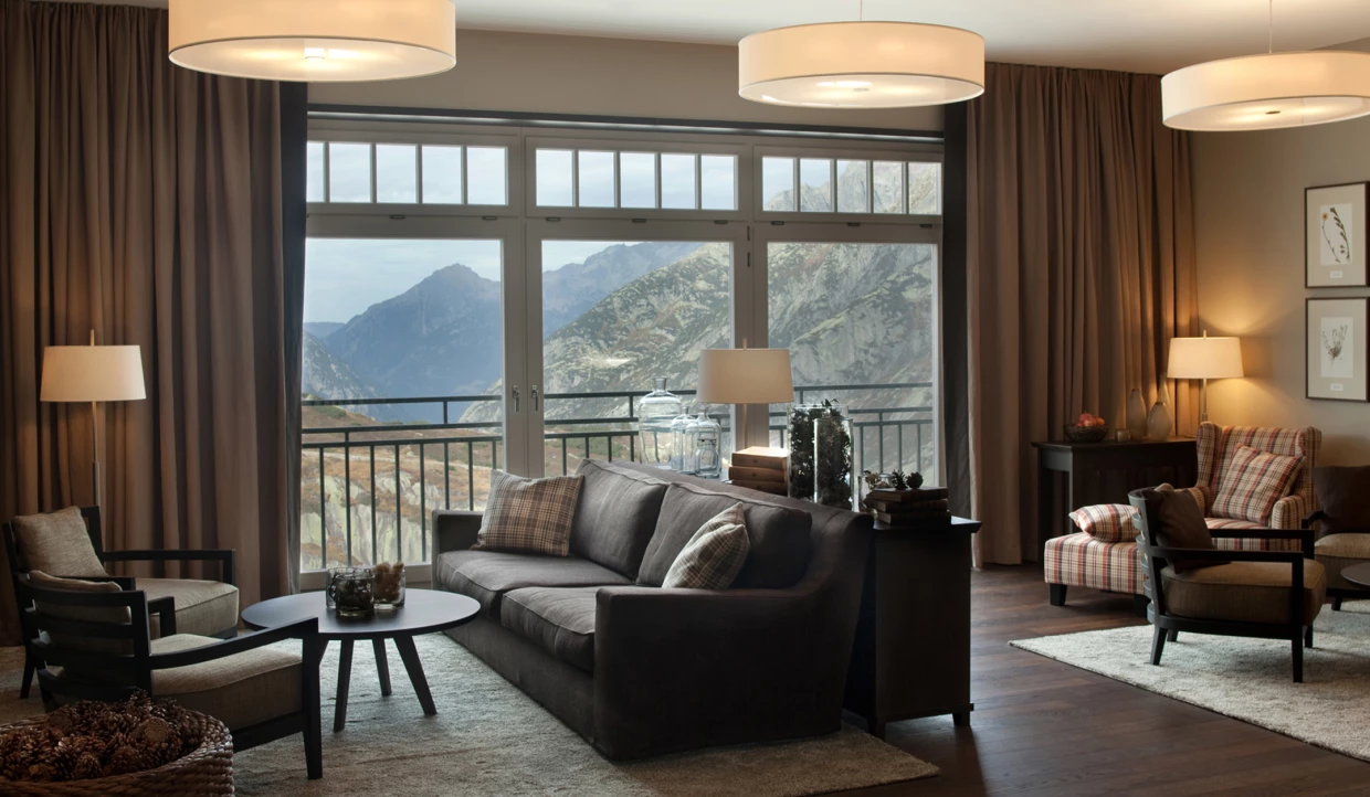 Wohnzimmer mit Blick auf Berge durch große Fenster.