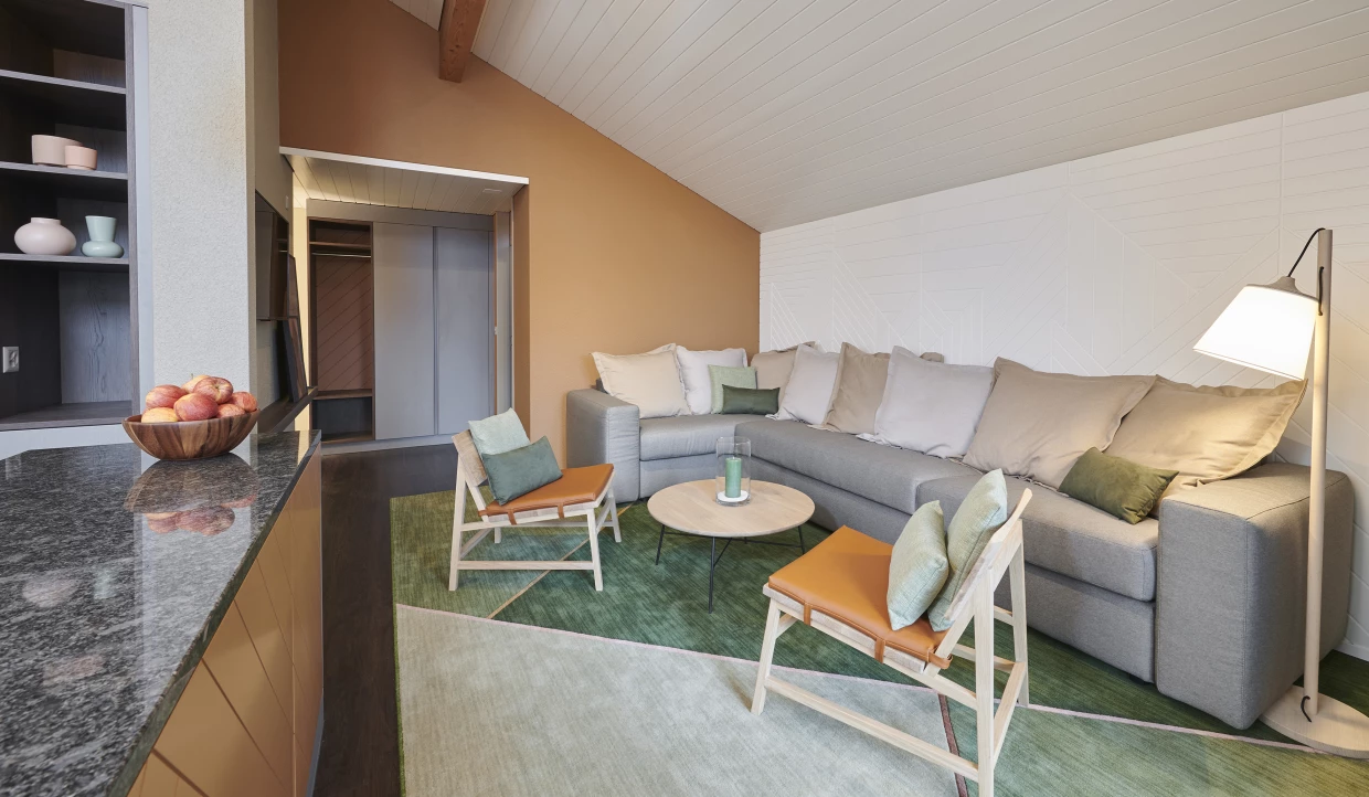 Wohnzimmer mit großer grauer Couch und Sessel, grüner Teppich