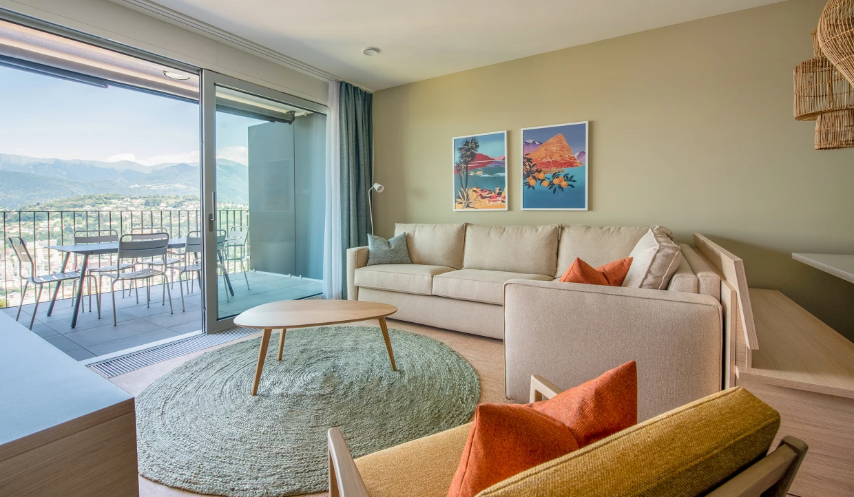 Wohnzimmer mit Sofa, Kunstbildern und Balkonblick