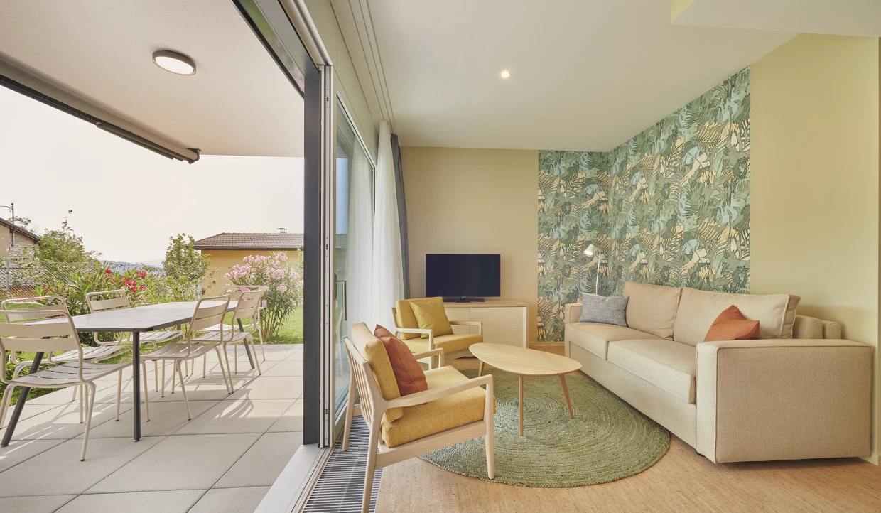 Wohnzimmer mit Sofa und Zugang zu Terrasse mit Gartenmöbeln