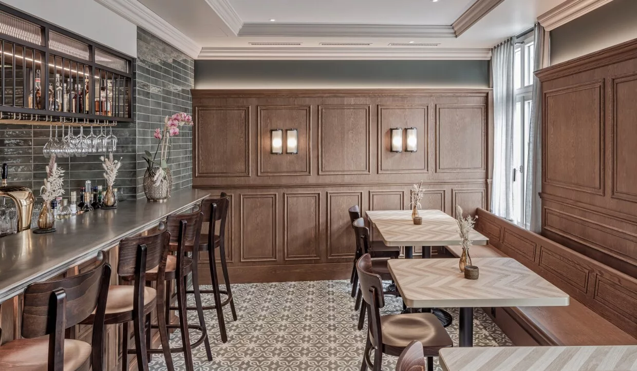 Bar eines modernen Landgasthauses mit Barhockern und gemustertem Fliesenboden
