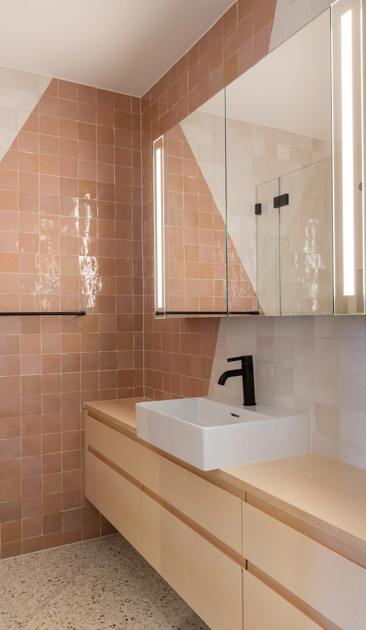 Badezimmer mit rosa Fliesen, Spiegel und Waschbecken