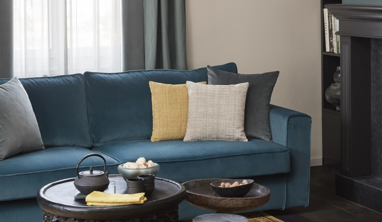 Blaues Sofa mit dekorativen Kissen und Beistelltisch mit Teekanne