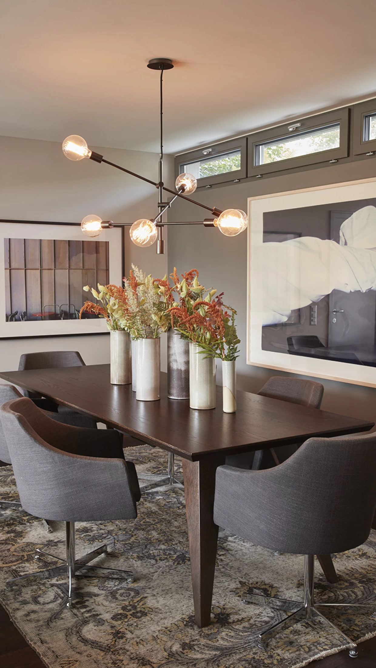 Dining room with flowers in tall vases on the table, modern lighting
