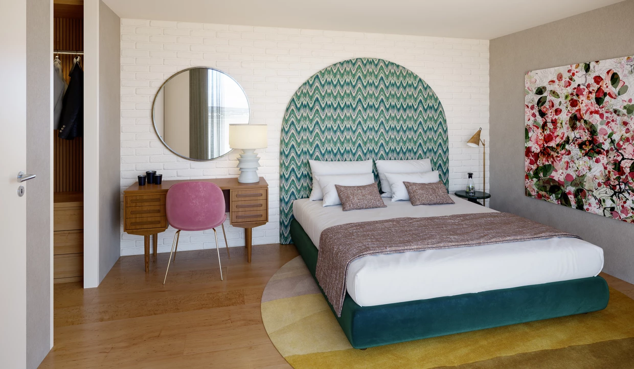 Gästezimmer mit Bett, gepolstertem blauen Kopfteil, pinkem Stuhl und Bildern an der Wand