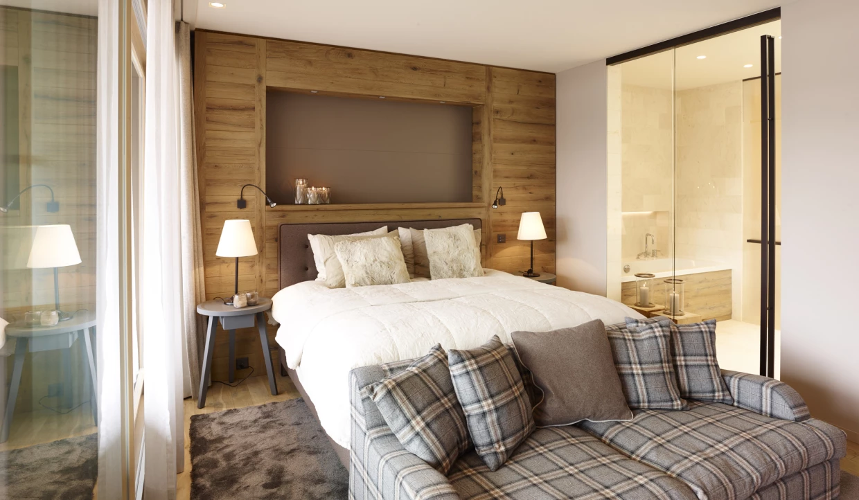 Gemütliches Schlafzimmer mit Bett, Sofa und großen Fenstern