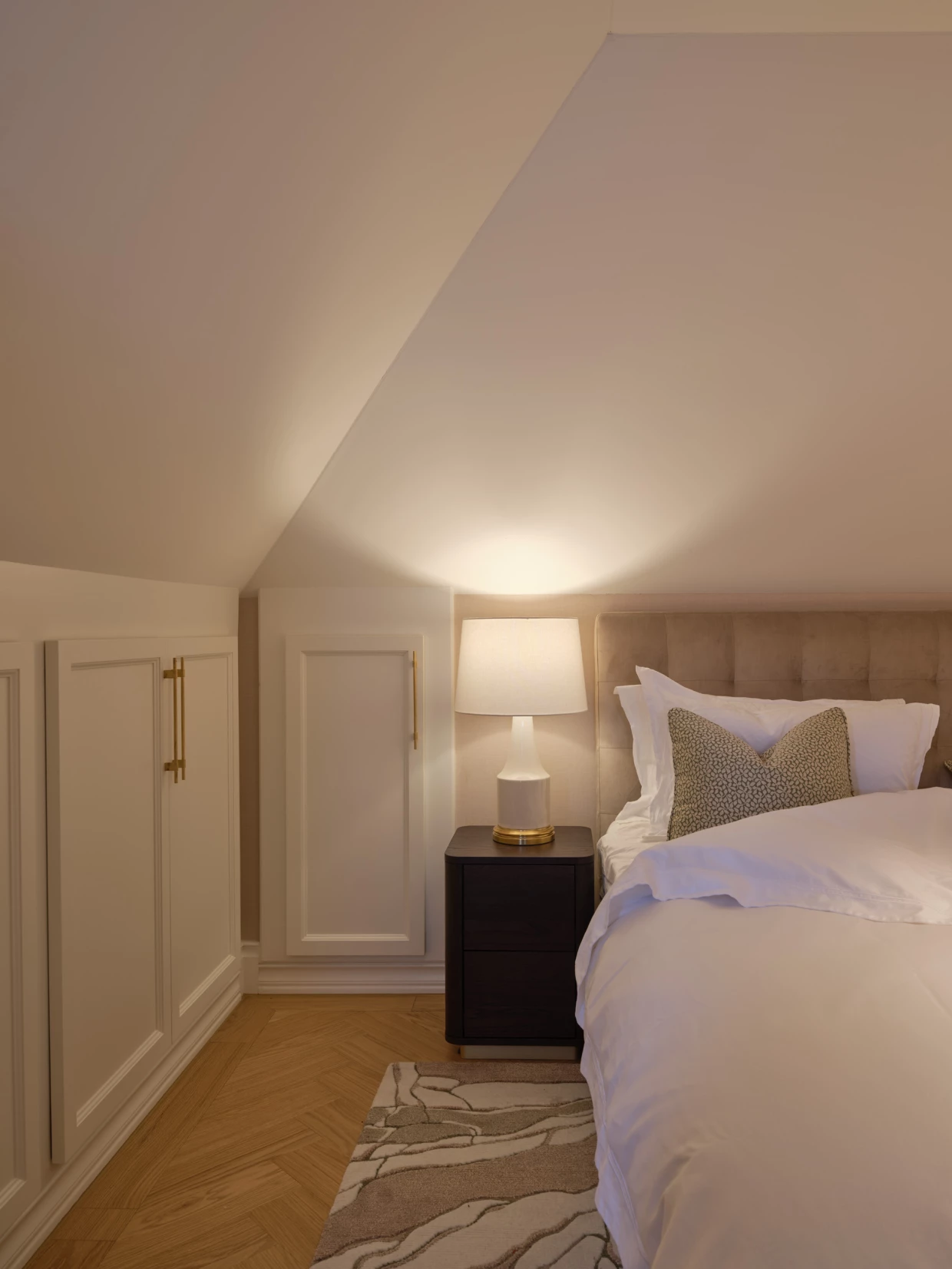 Gemütliches Bett unter Dachschräge mit Nachttischlampe