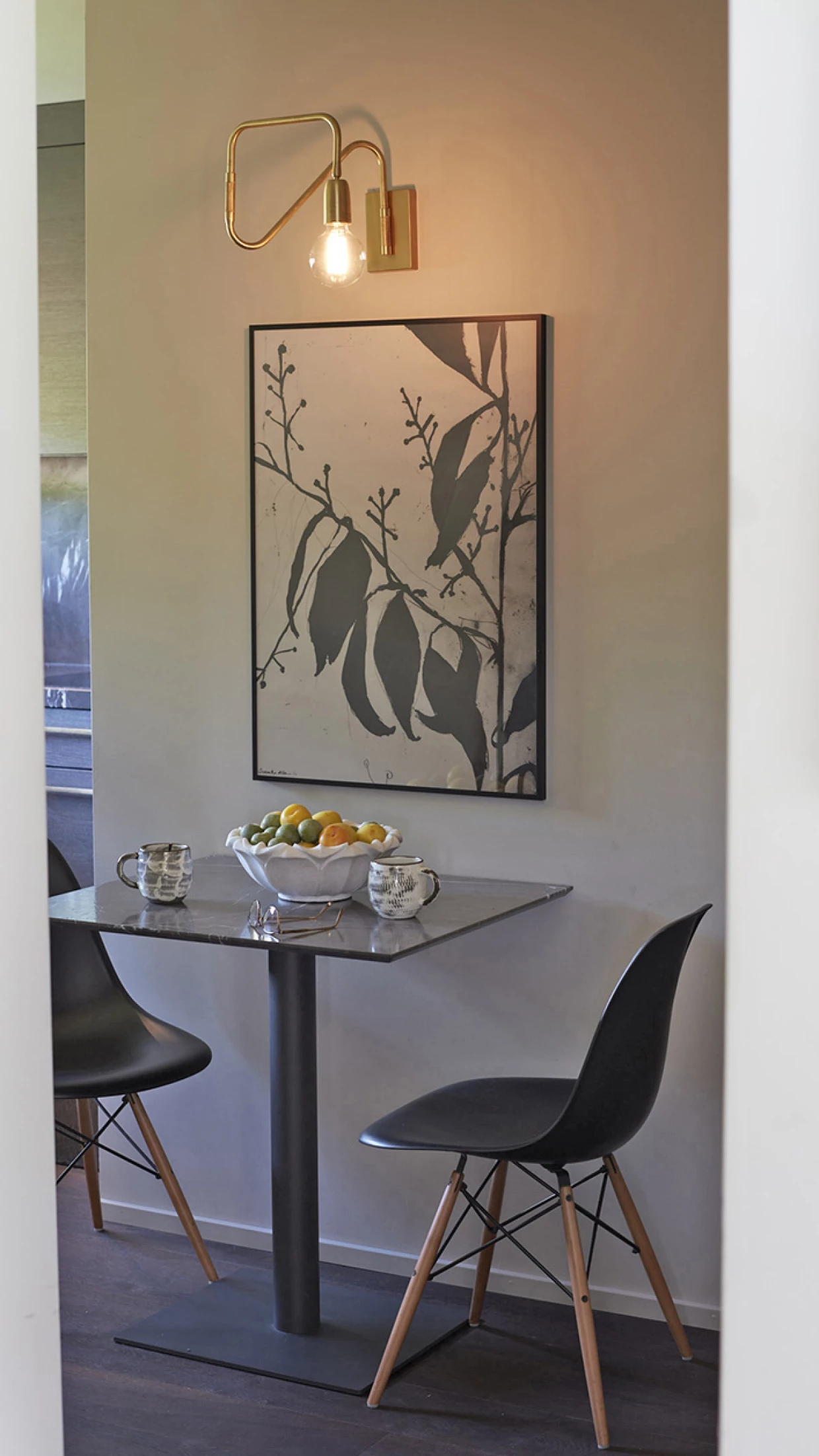 Small dining area with round tabletop, two chairs, and wall art