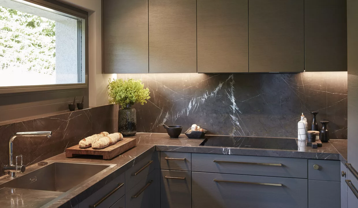Moderne Küche mit Arbeitsfläche aus Marmor, Pflanzen und frischen Broten