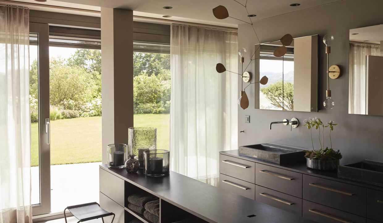Modern bathroom with dark furniture and large window with curtains