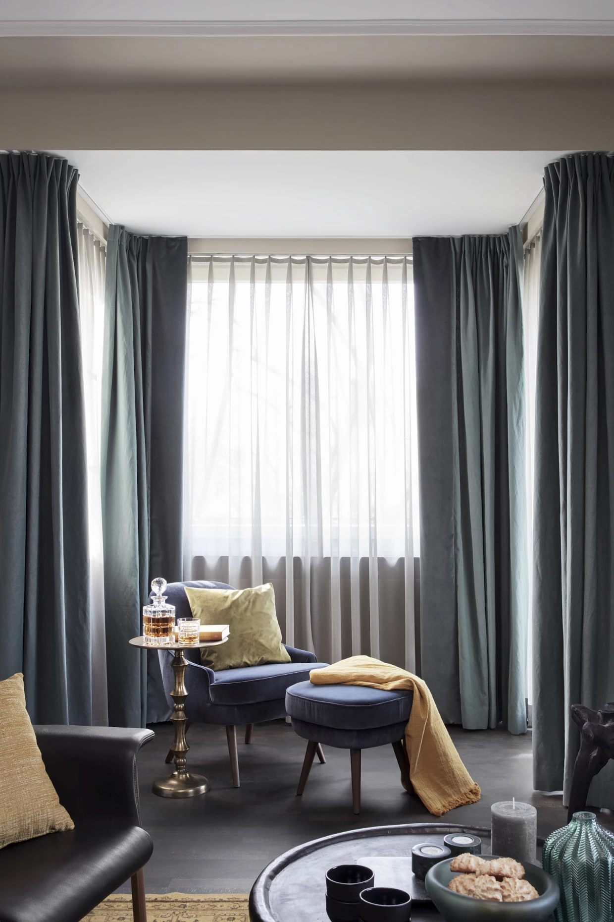 Raum mit blauen Vorhängen, Sesseln und kleinem Tisch