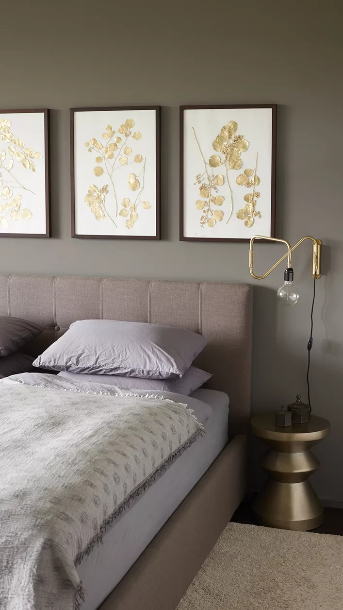 Schlafzimmer mit gepolstertem Kopfteil und botanischen Bildern an der Wand