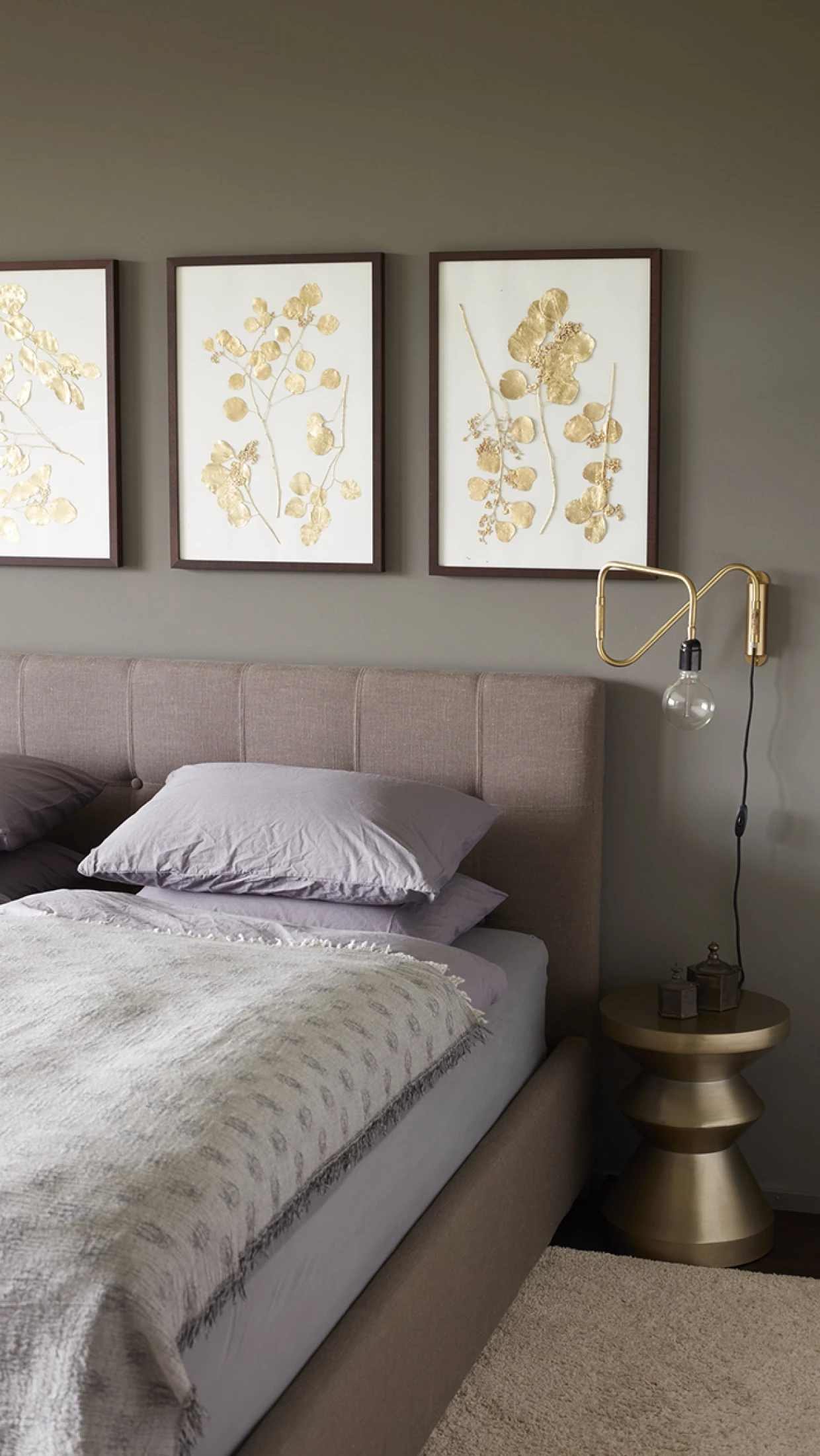 Bedroom with upholstered headboard and botanical pictures on the wall