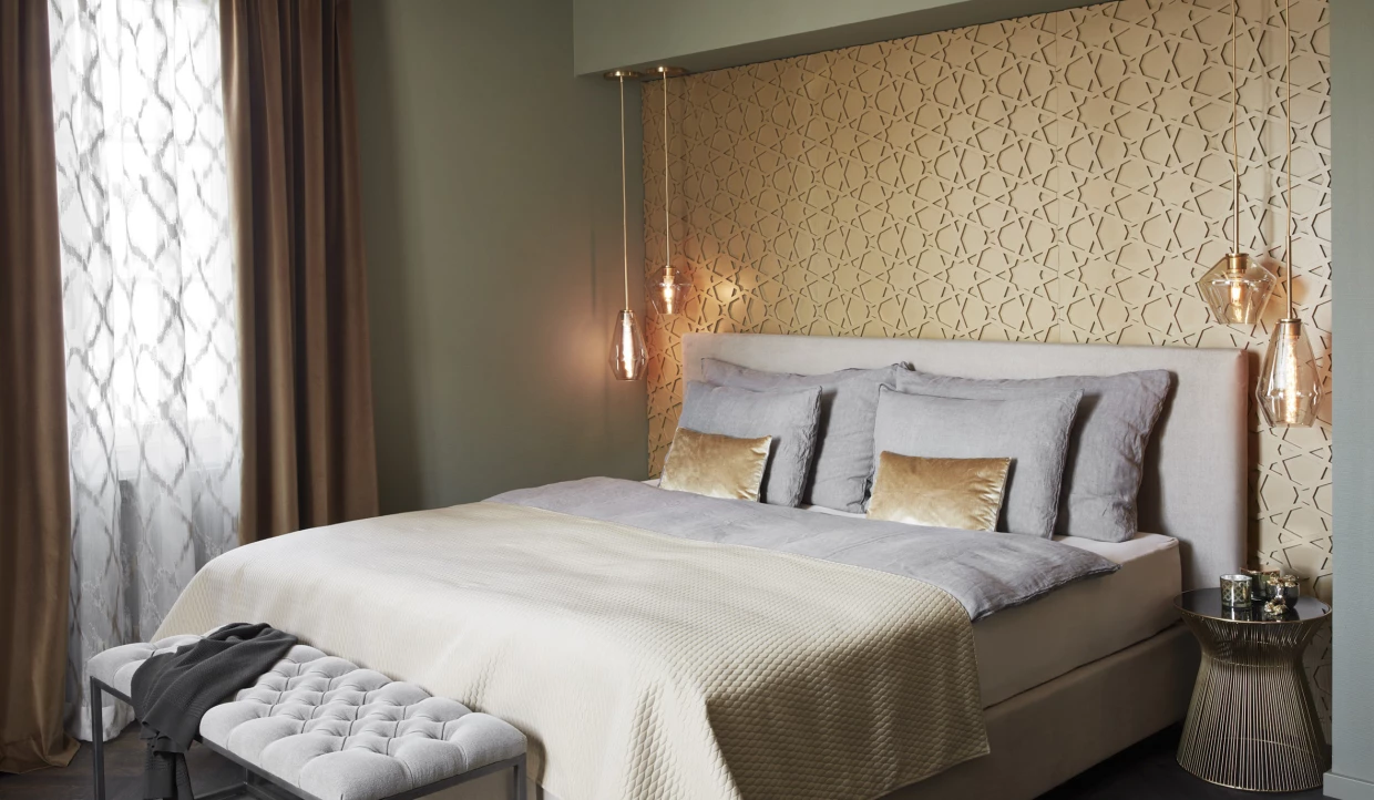 Schlafzimmer mit grauem Bett, goldener Wand und Vorhängen