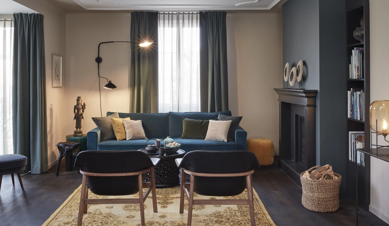 Sitzecke mit blauem Sofa, Kissen und zwei Stühlen