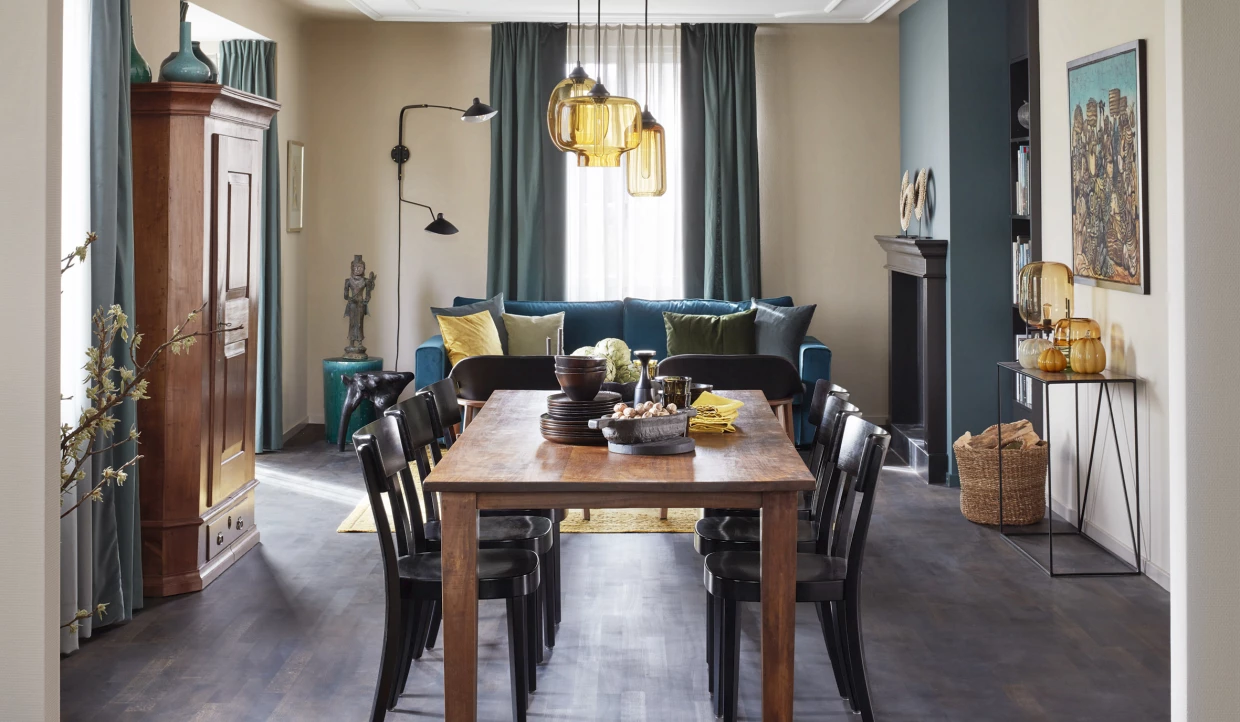 Wohnzimmer mit Esstisch, blauer Couch und dekorativen Lampen
