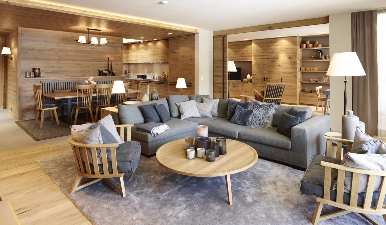 Wohnzimmer mit grauem Sofa, Holztisch und offener Küche