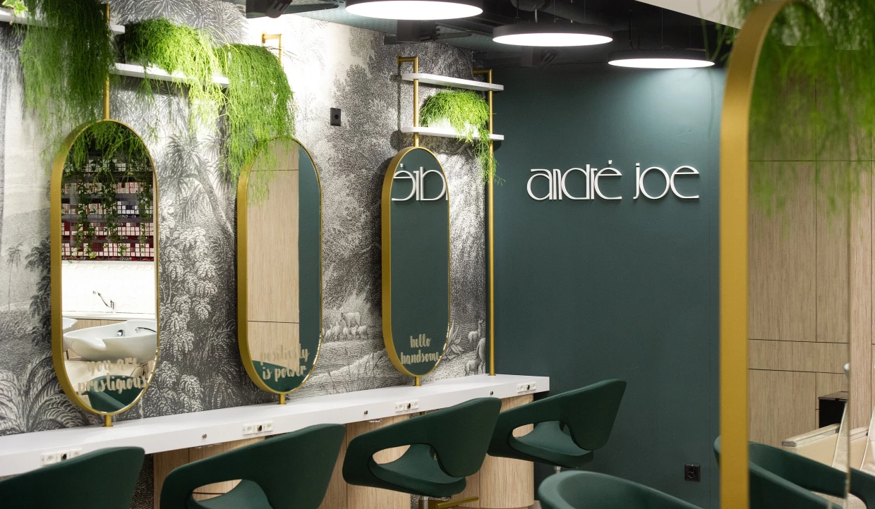 Moderner Friseursalon mit grünen Stühlen, Spiegeln und Pflanzen