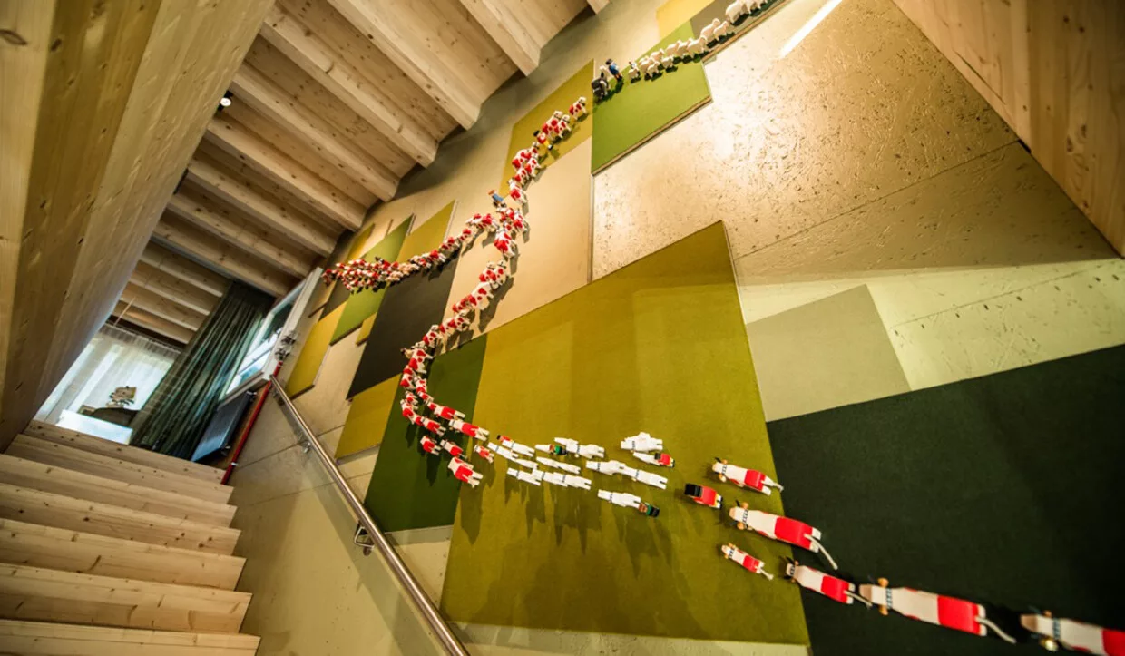 Wanddekoration aus aufgefädelten Kuhfiguren neben Treppe