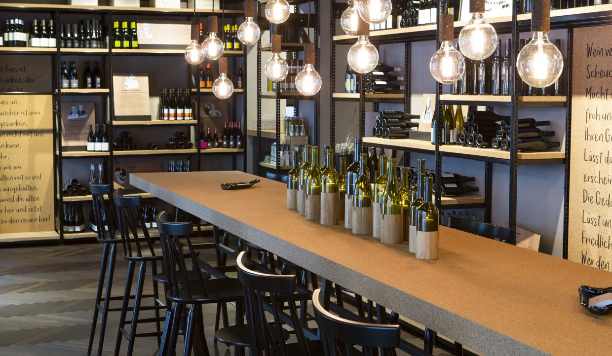 Weinregale und langes Tischset mit Flaschen und Gläsern