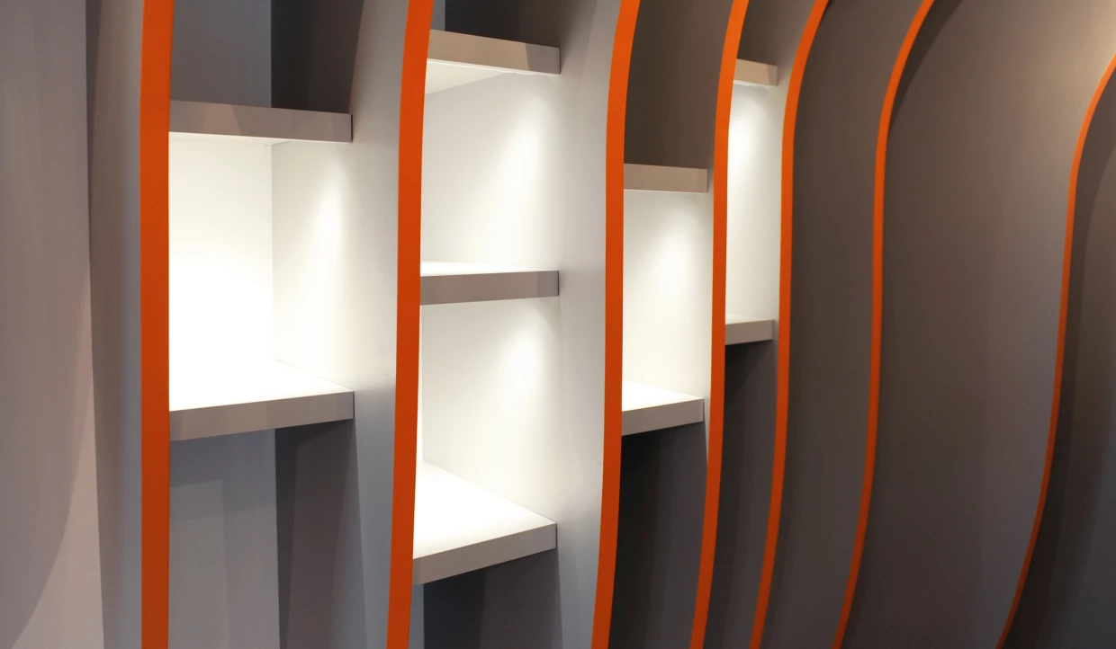 Weiße Regale mit orange umrandeten Fächern an der Wand