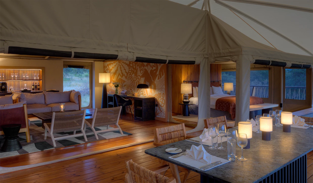 Luxuriöses Safari-Zelt am Abend mit Esstisch, Sofa und Schreibtisch