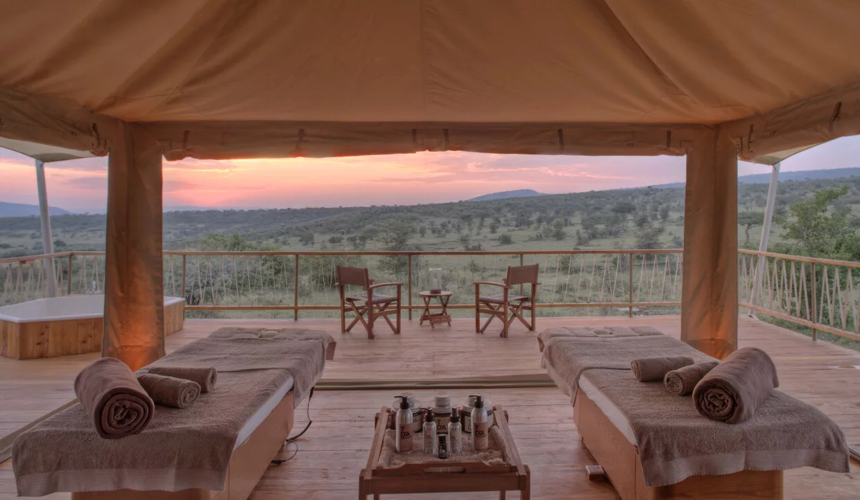 Wellness-Zelt in einem Luxus-Safari-Camp. Blick über Massage-Liegen über die Terrasse in die afrikanische Natur.