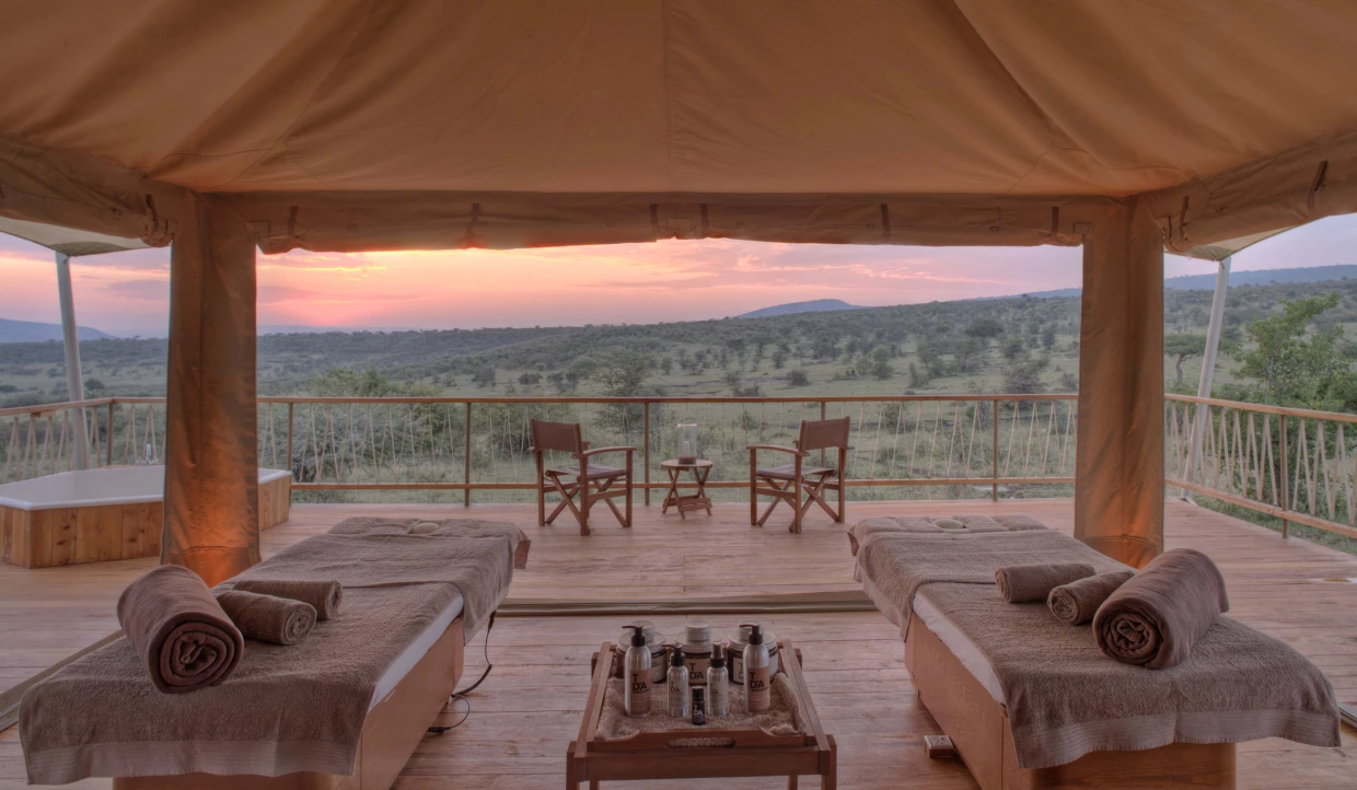 Wellness tent in a luxury safari camp. View over massage tables across the terrace into the African wilderness.