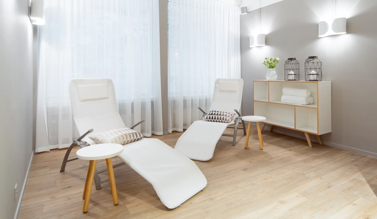 Two white lounge chairs in a room with curtains